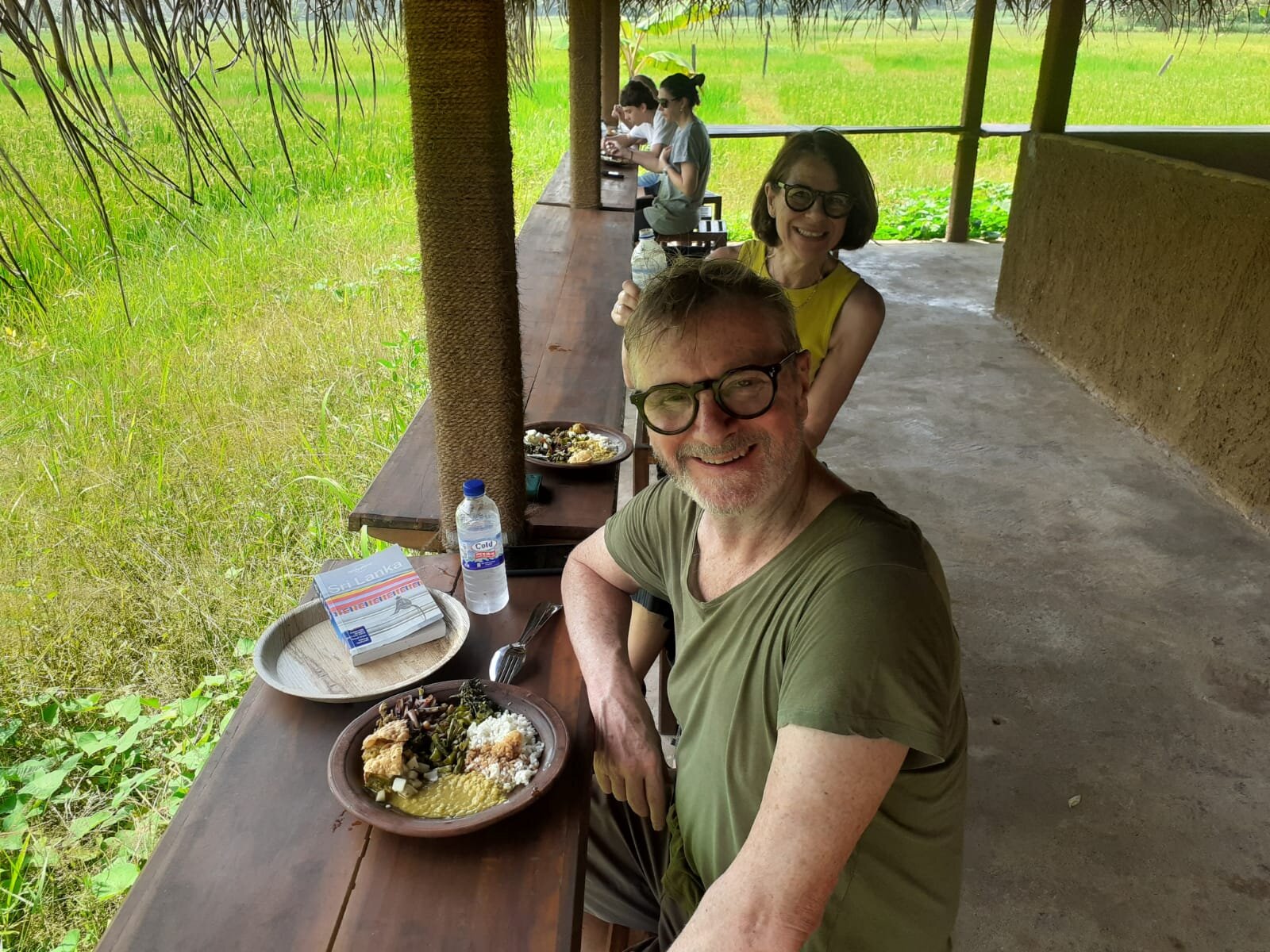 Real guests sharing a traditional Sri Lankan lunch by a rice paddy
