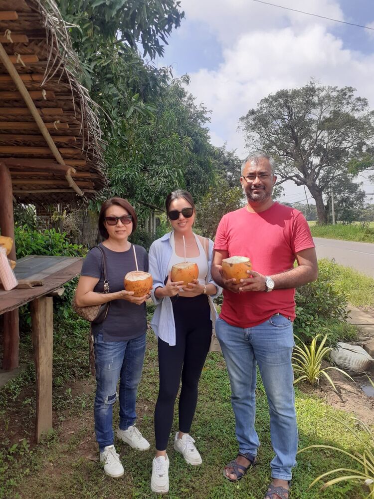 Guests holding king coconuts at a roadside stop
