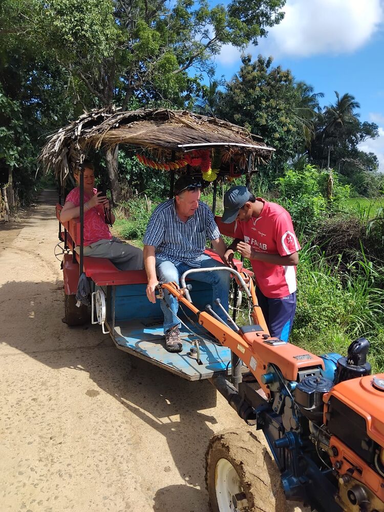 Guest riding a traditional farm cart with a local driver, Sri Lanka village road
